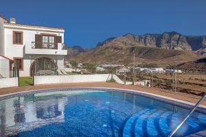 a swimming pool in front of a house with a mountain at Villas Sicilia in Agaete