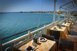 a balcony of a cruise ship with tables on the water at Hotel La Riva in Giardini Naxos