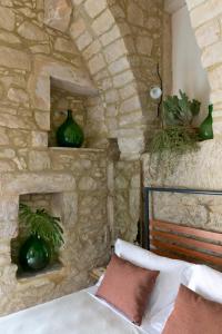 een slaapkamer met stenen muren, een bed en een stenen open haard bij Casa Santa Maria - Fichi d'india in Ragusa