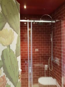 een badkamer met een douche en een rode bakstenen muur bij Casa Santa Maria - Fichi d'india in Ragusa