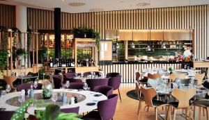 ストックホルムにあるクラリオン ホテル サインのテーブルと紫の椅子のあるレストラン、バー