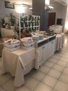 una linea a buffet con tavoli bianchi con sopra cibo di Hotel Smeraldo a Brenzone sul Garda
