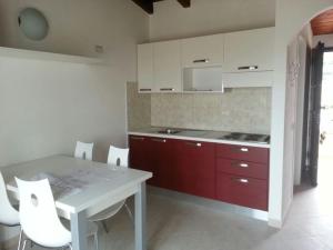 une cuisine avec une table blanche et des placards rouges dans l'établissement Residence L'Incanto Attici, à Castelsardo