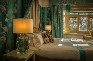 a bedroom with a bed with a lamp and a window at Fischers Baslow Hall - Chatsworth in Baslow