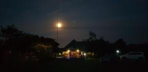 Una casa iluminada con una luna en el cielo en Tranquillity Day Spa & Lodge, en Baviaanspoort