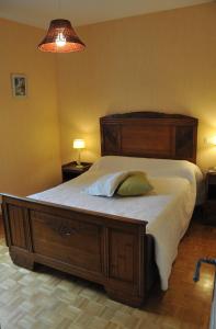 1 dormitorio con cama grande de madera y almohada en Gîte Les aurégats, en Maligny