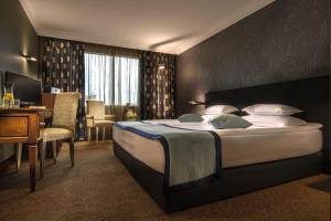 a hotel room with a large bed and a desk at Rosslyn Thracia Hotel Sofia in Sofia