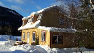 une maison jaune avec de la neige sur le toit dans l'établissement Grangette Entre Chiens et Loups, à LʼAnse-Saint-Jean