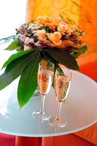 two champagne glasses on a table with a bouquet of flowers at Hotel an der Ilse in Lemgo