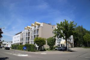 un grande edificio bianco con le auto parcheggiate di fronte di Comfort Boardinghouse a Stoccarda