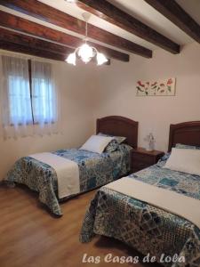a bedroom with two beds and a chandelier at Las Casas de Lola in Rabago