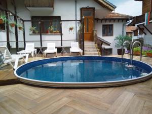 a pool in a yard with chairs and a house at Guest House Unika in Tryavna +76 photos