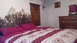 a bedroom with a bed with purple sheets and a dresser at Tana del Paradiso in Baceno