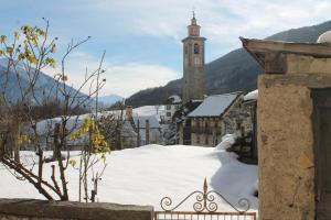 a small town with a clock tower in the snow at Tana del Paradiso in Baceno