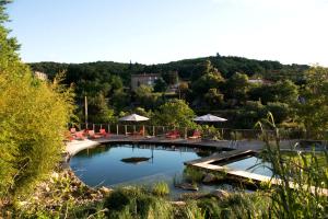 une grande piscine avec des chaises et des parasols dans l'établissement Domaine Riberach - Restaurant étoilé - Spa - Piscine naturelle - Vignoble bio, à Bélesta