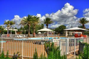 a swimming pool with umbrellas and palm trees at Bungalows Los Melocotones in Maspalomas