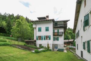 a white house with green shuttered windows and a yard at Casa Silva in Falcade