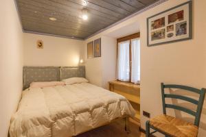 a small bedroom with a bed and a chair at Casa Silva in Falcade