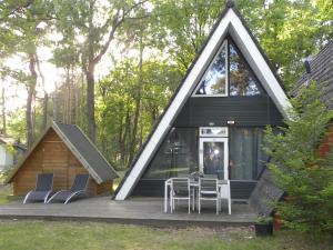 una casa con techo triangular con sillas y mesa en Bungalows Bospark te Stramproy, en Stramproy