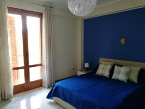 ein blaues Schlafzimmer mit einem Bett und einem großen Fenster in der Unterkunft New Panoramic Apartment in Noto
