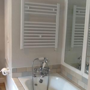 a bathroom with a bath tub with a window and a mirror at Swan Cottage in Coxwold