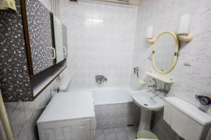 a white bathroom with a sink and a tub and a mirror at Apartamenty Iława in Iława