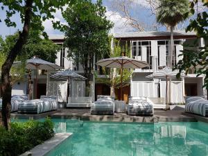 - une piscine avec des chaises et des parasols à côté d'une maison dans l'établissement Treevana Club Chiangmai, à Chiang Mai