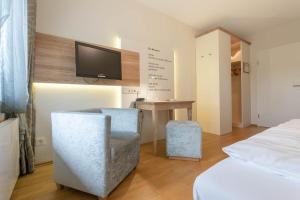 a bedroom with a bed and a desk and a tv at Hotel im Auerbachtal in Bad Laasphe