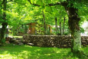 un muro di pietra e una baita di tronchi nel bosco di Camping La Châtaigneraie a Gravières