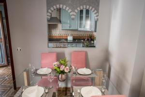 a dining room with a glass table and pink chairs at El Pilar Home in Córdoba
