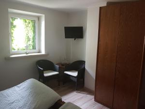 a bedroom with a bed and two chairs and a window at Forellenhof-Waldhölzbach in Waldhölzbach