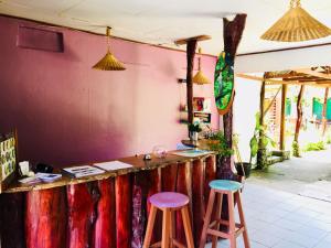 卡維塔的住宿－Cabinas Palmer Makanda，粉红色墙前有两个凳子的酒吧