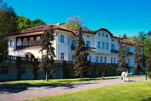 a building with two people walking in front of it at Apartman A9 Lux in Banja Koviljača