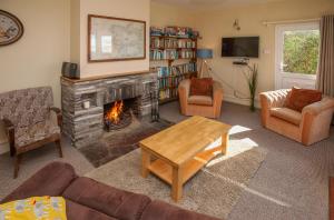 Cottage 202 - Renvyle في رينفيلي: غرفة معيشة بها موقد وأريكة وكراسي