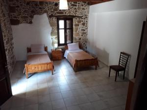 a bedroom with two beds and a chair at Traditional House Koukounara in Kissamos