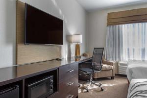a hotel room with a desk with a television and a bed at MainStay Suites in Big Spring