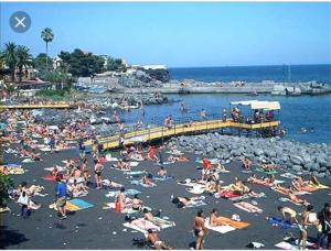 a crowd of people on a beach with a pier at Luxurious Street Apartments in Catania