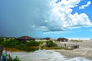 a beach with some huts and a cloudy sky at Casa Dunas da Barrinha in Barrinha