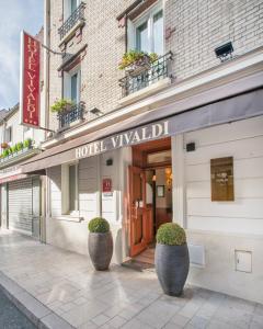 a hotel villelli building with two large pots in front of it at Hotel Vivaldi in Puteaux