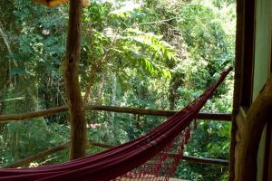 a hammock in front of a window in a forest at La Aldea De La Selva Lodge in Puerto Iguazú
