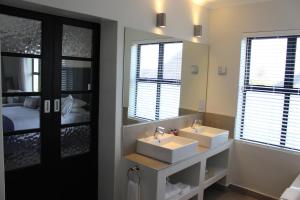 un bagno con due lavandini, uno specchio e un letto di Whale Rock Luxury Lodge a Hermanus