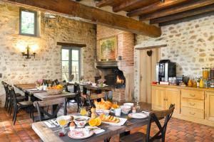 a dining room with wooden tables and chairs and a kitchen at Moulin des Templiers Hôtel & SPA in Pontaubert