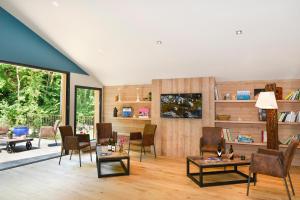 a living room with chairs and tables and a large window at Moulin des Templiers Hôtel & SPA in Pontaubert