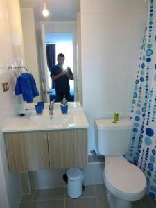 a man taking a picture of a bathroom with a toilet at Departamento Ricardo in Viña del Mar