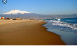 a beach with a snow covered mountain in the background at Luxurious Street Apartments in Catania