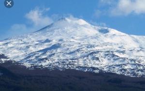 a mountain covered in snow on top at Luxurious Street Apartments in Catania