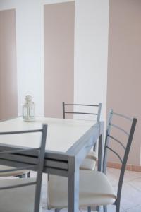 een eettafel en stoelen met een witte tafel bij Appartamento Il Castello in Casale Monferrato