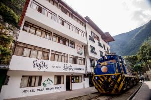 un tren está estacionado frente a un edificio en Casa Machu Picchu Hostel, en Machu Picchu