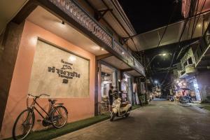 una moto estacionada en el lateral de un edificio por la noche en Tamajun Hotel, en Chanthaburi