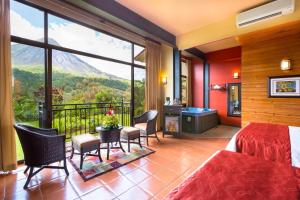 a bedroom with a bed and a balcony with a view at Hotel Arenal Kioro Suites & Spa in Fortuna